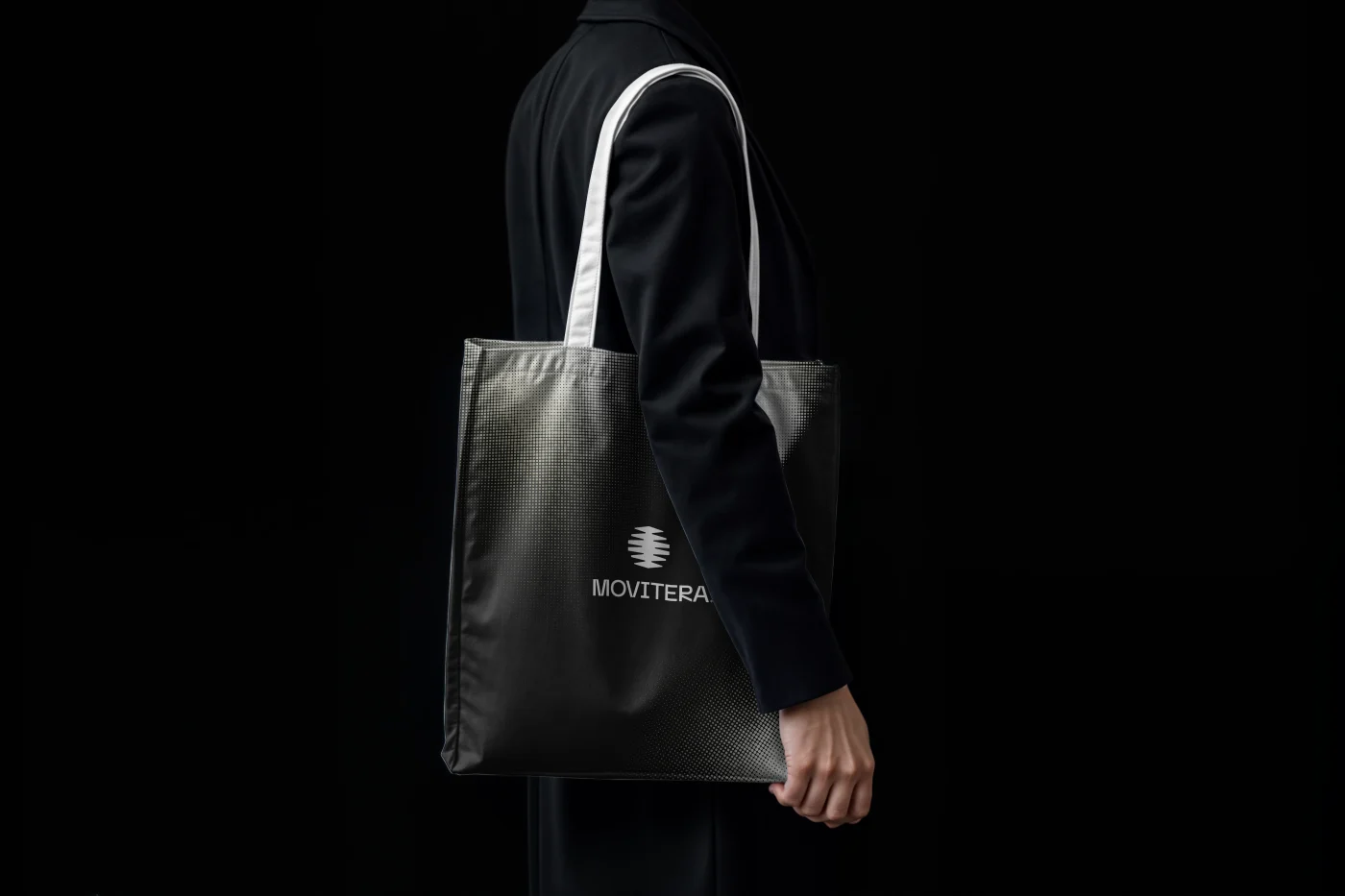 Identidade da Movitera aplicada em uma bolsa preta com textura reticulada.