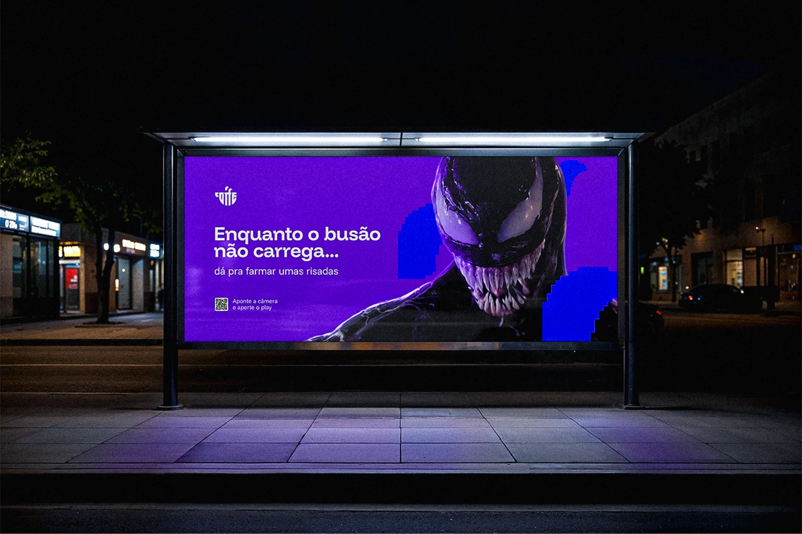 Abrigo de ônibus iluminado à noite com o anúncio "Enquanto o busão não carrega...".