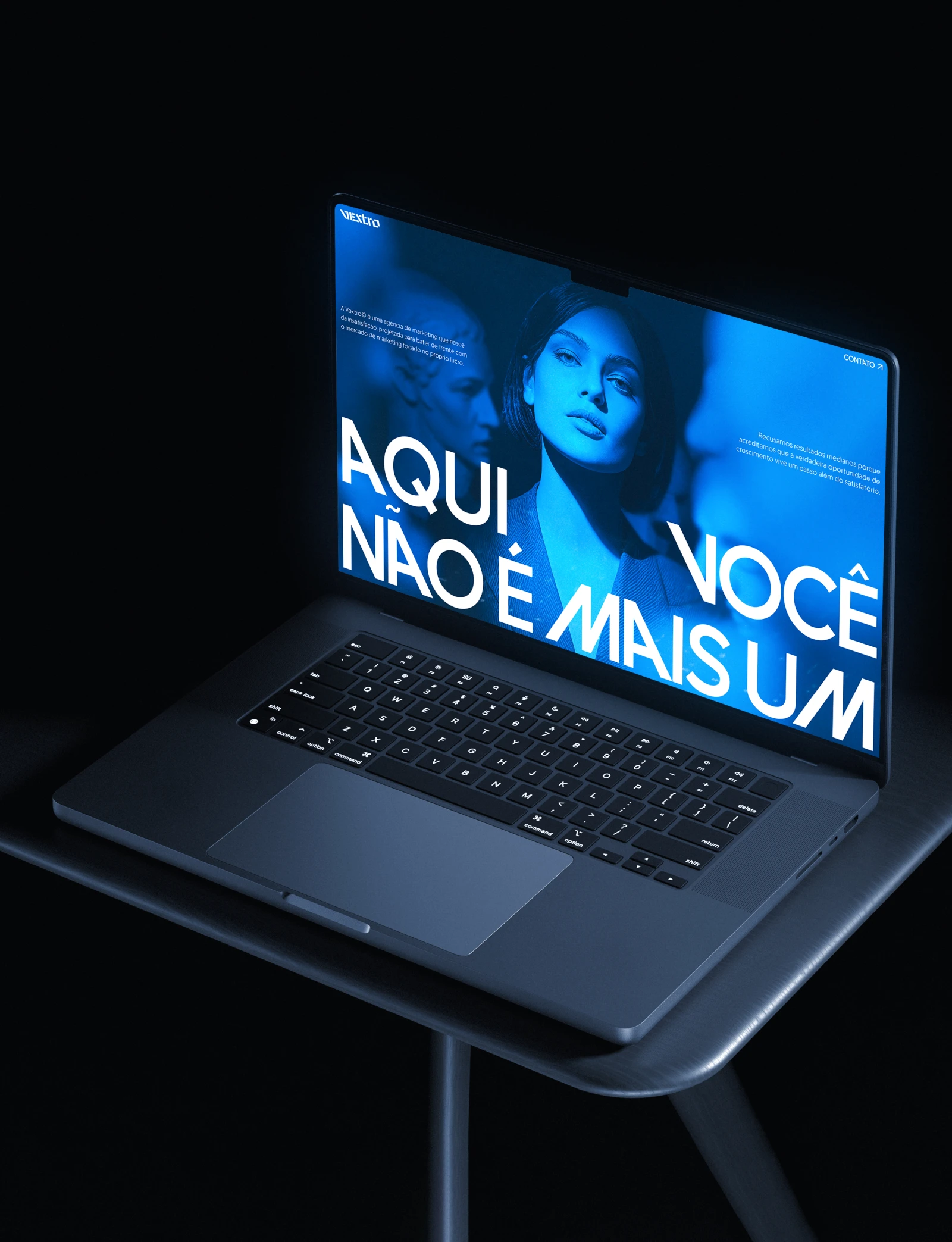 Notebook sobre uma mesa escura exibindo a home da Vextro em azul.